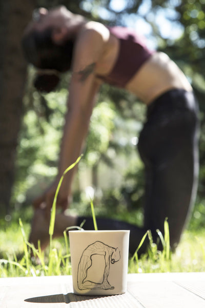 white coloured outside, light green coloured inside Camel yoga pose drawn mug with a posing yogi background