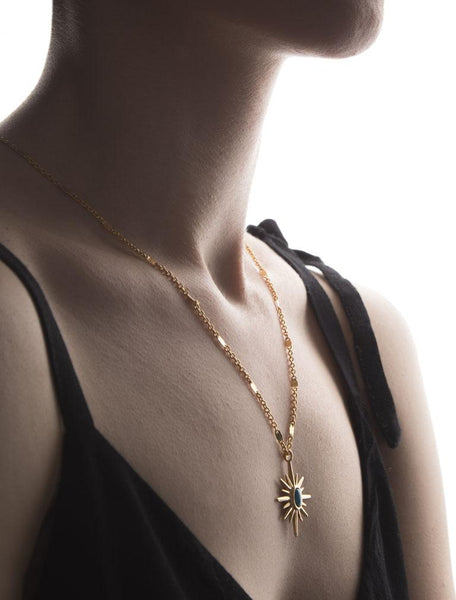 gold necklace with sun figure which has blue stone in it