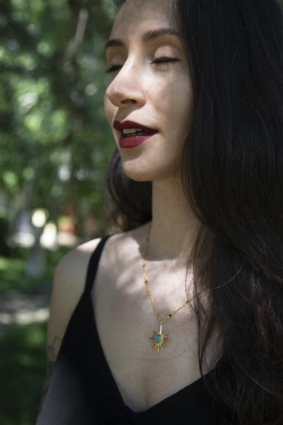 gold necklace with sun figure which has blue stone in it