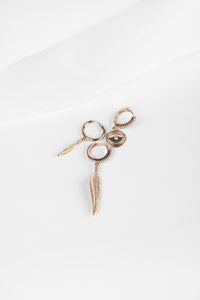 two leaf shaped, one eye shaped golden earring set. they are detailed with tiny white stones on them. 