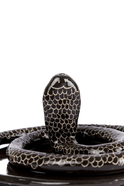 zoomed in snake shaped incense burner with plate under it in black colour